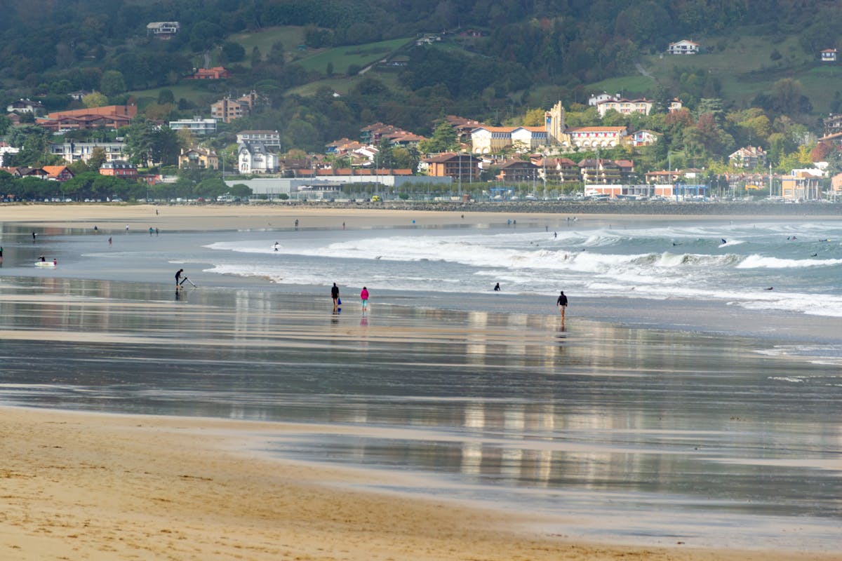 Serene view of Playa de Santa Marina with people enjoying the sandy beach and waves in Ribadesella, Spain. Playa de ribadesella